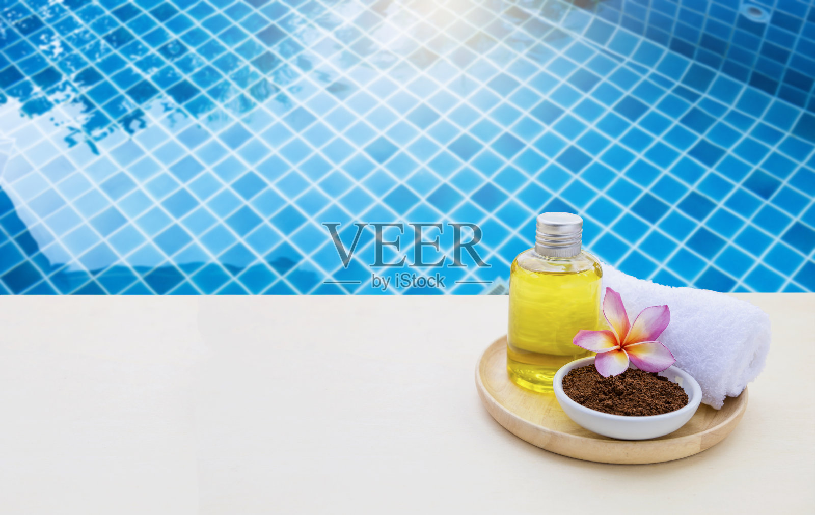 咖啡粉磨砂膏和按摩油与鸡蛋花和毛巾在泳池边照片摄影图片