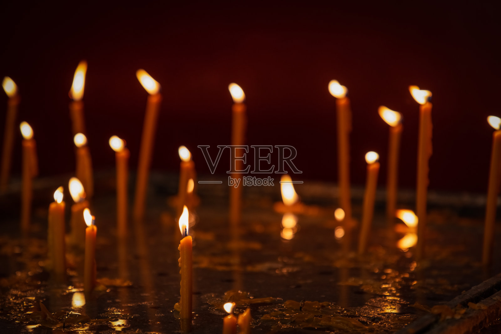 没有聚焦的融蜡细蜡烛,带着小火焰站在黑暗的教堂蜡烛桌上,只有前面的蜡烛在前景是焦点,宗教概念照片摄影图片