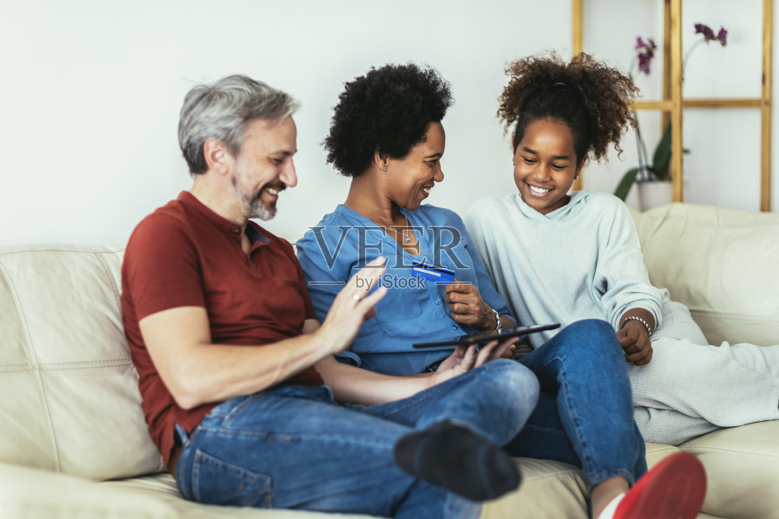 家庭使用数码平板电脑和信用卡在家里进行网上购物。照片摄影图片