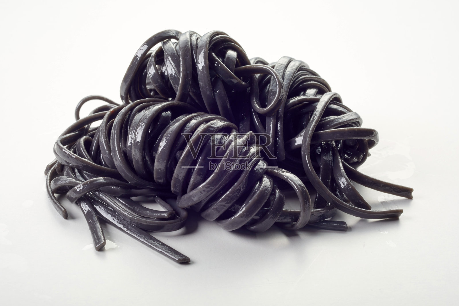 特写,一堆美味的黑色意大利面在白色背景上照片摄影图片