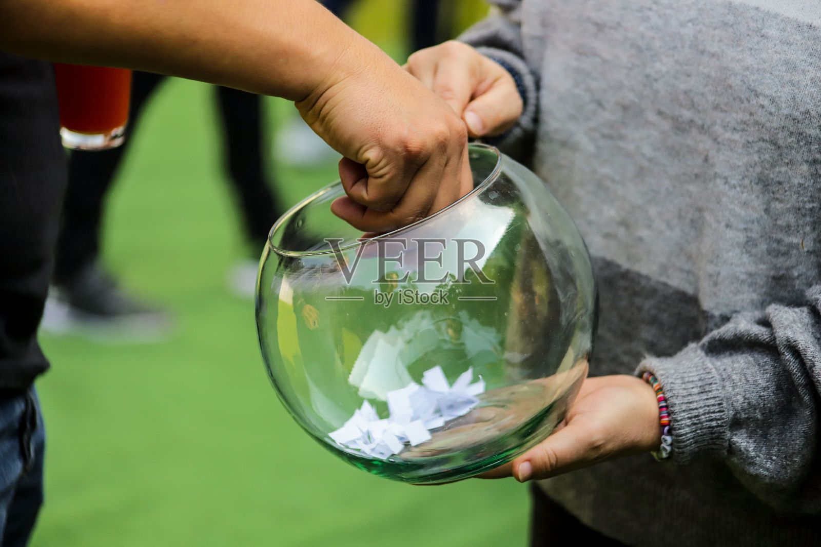 一个人的手从一个透明的碗里拿一张纸条照片摄影图片