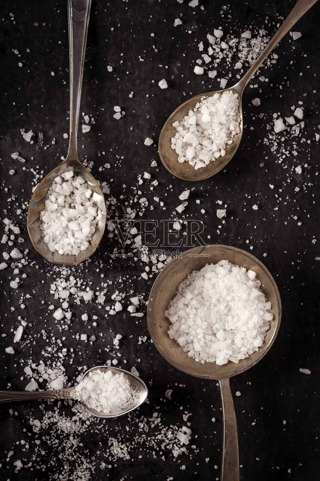 俯视图的四个勺子与粗粒海盐的黑色背景照片摄影图片