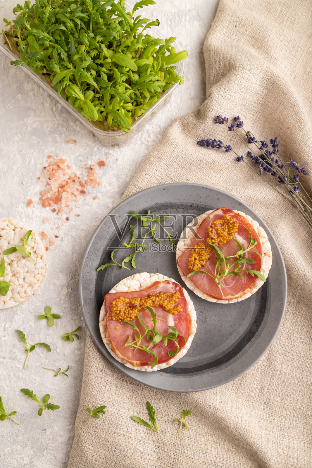 膨化年糕三明治配咸肉干,灰色混凝土上的微绿色,俯视图,特写。照片摄影图片