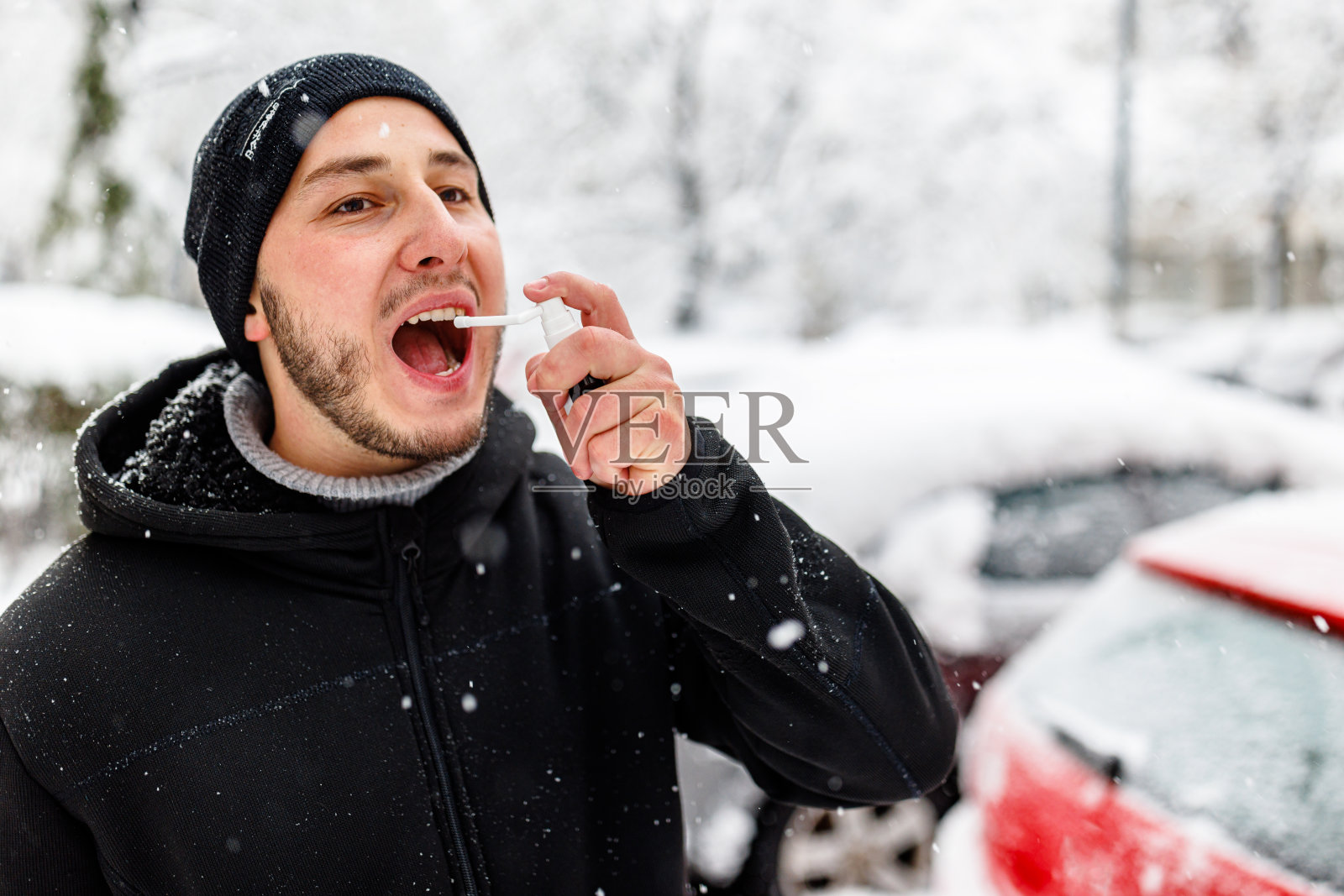 患有哮喘的年轻男子在冬天使用吸入器。照片摄影图片