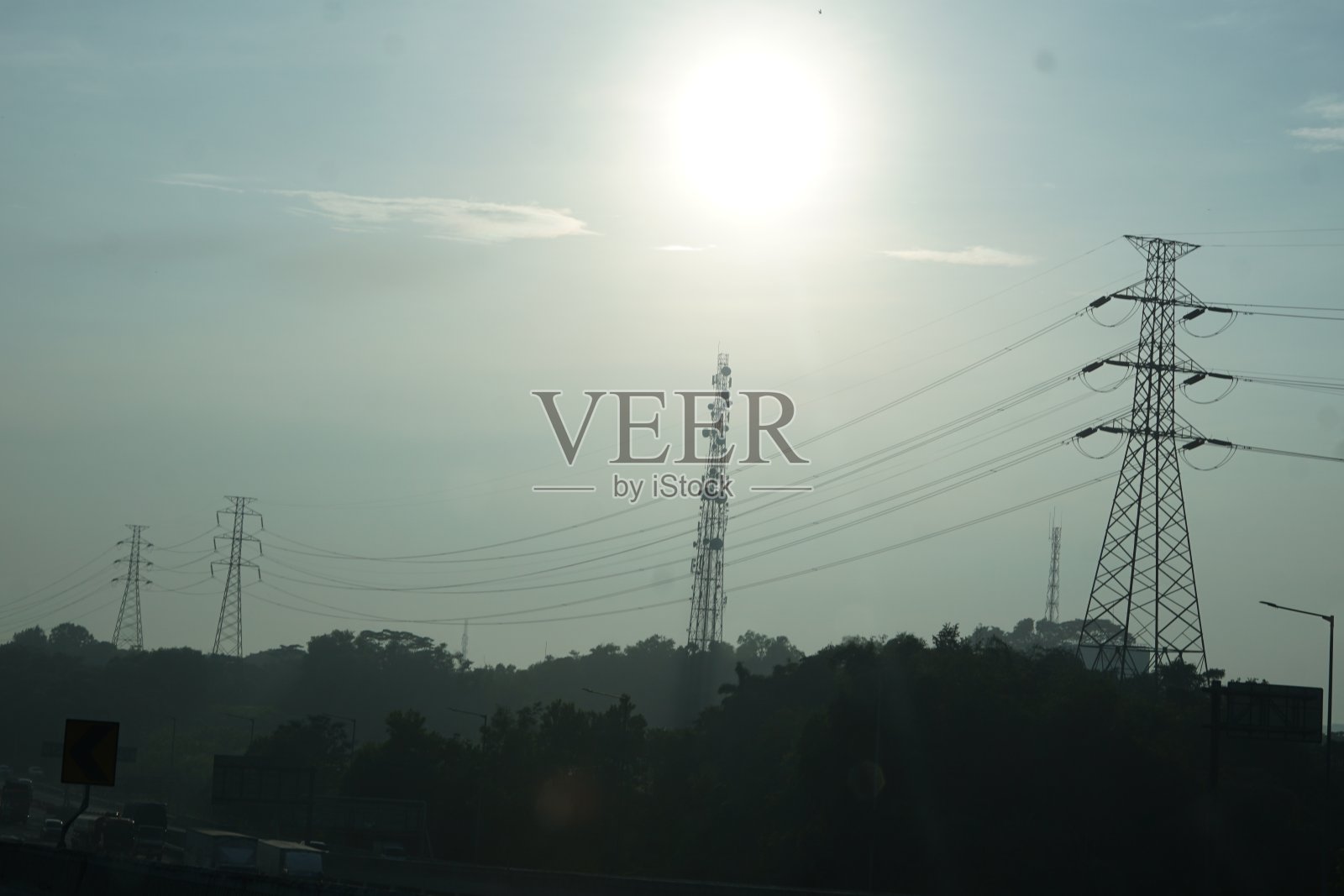 日落树影下的高压配电杆子,供能源发电技术行业用的输电塔线照片摄影图片