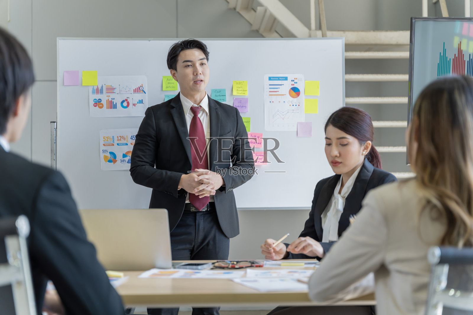 一群年轻的亚洲商人谈天说地,工作愉快,乐在其中。在公司的办公室照片摄影图片
