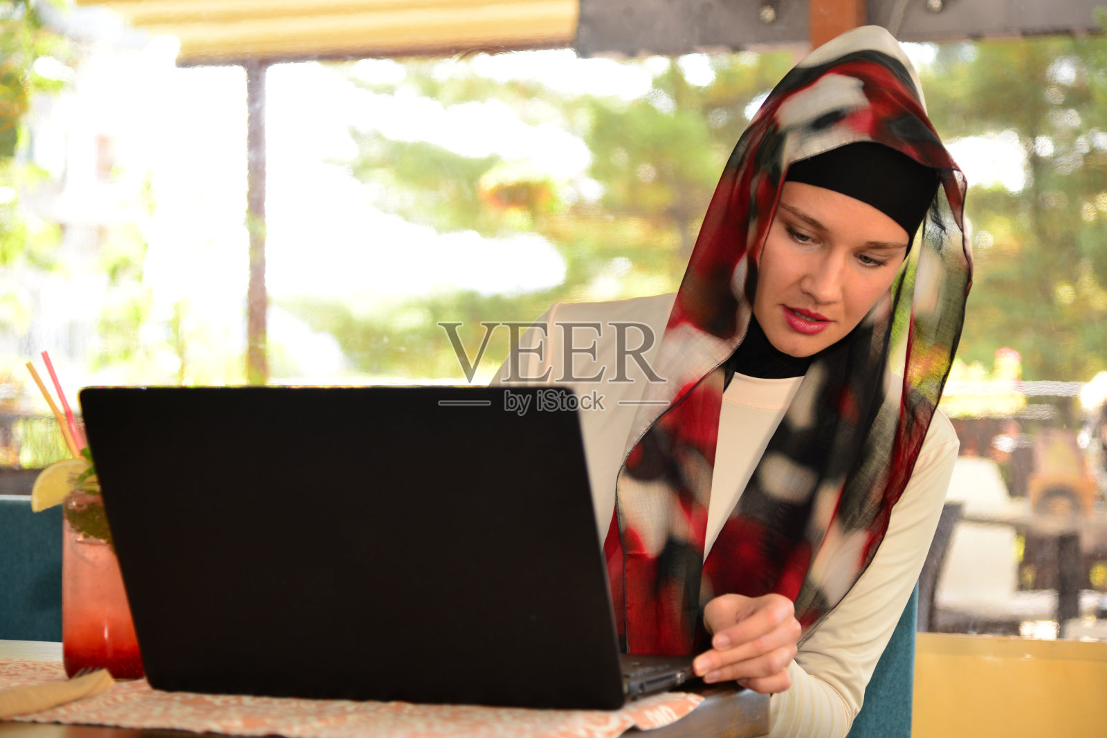 穆斯林女性自由职业者在咖啡馆工作。照片摄影图片