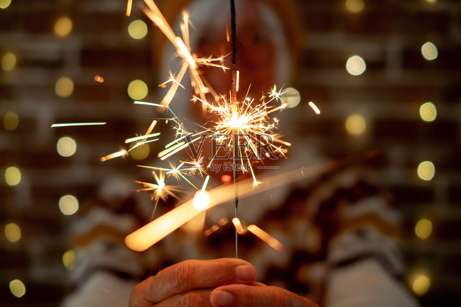 模糊的白人妇女在冬季毛衣拿着闪闪发光的灯,老太太庆祝圣诞节和新年在夜晚闪闪发光照片摄影图片