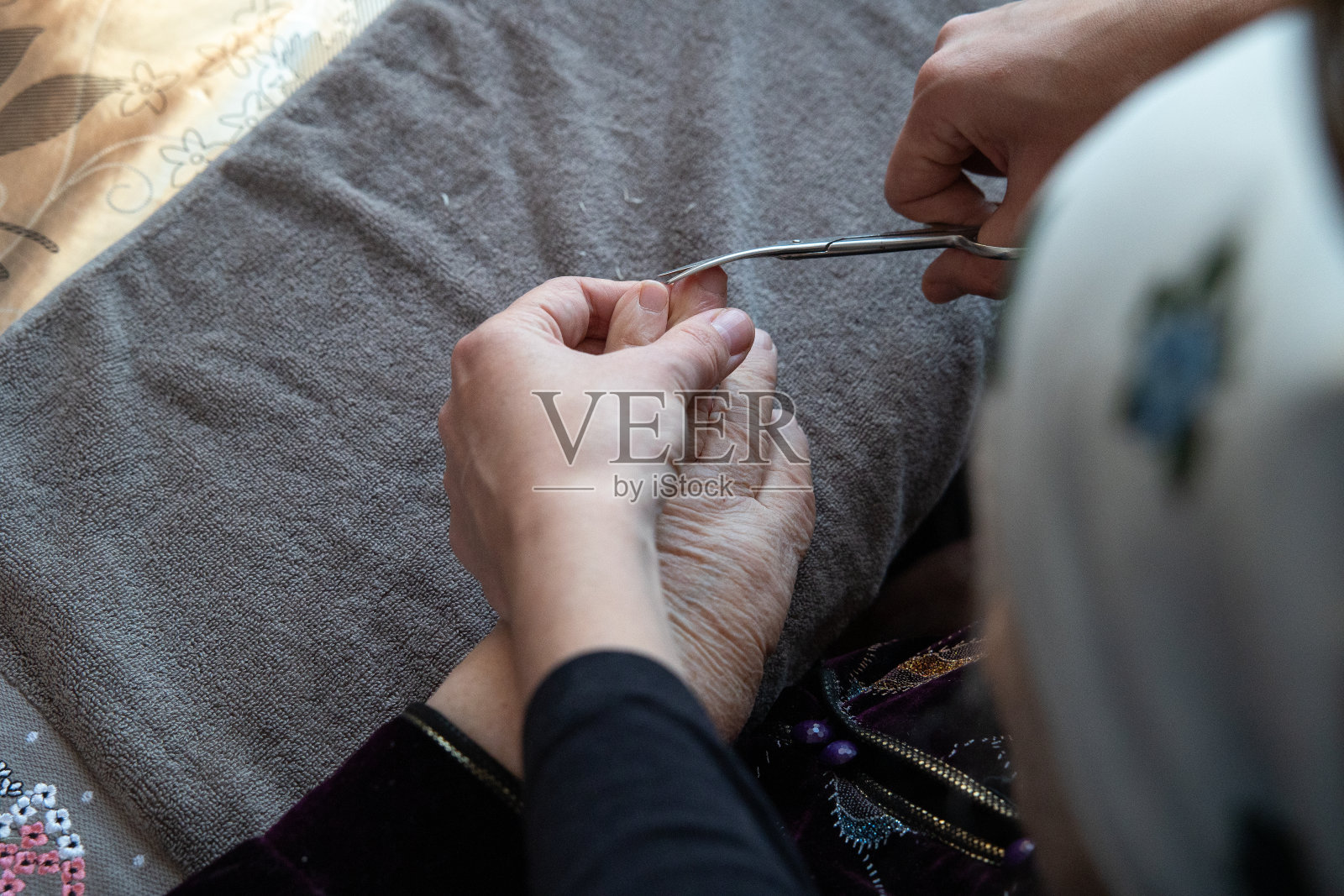 这个女人帮她的祖母剪指甲。照片摄影图片