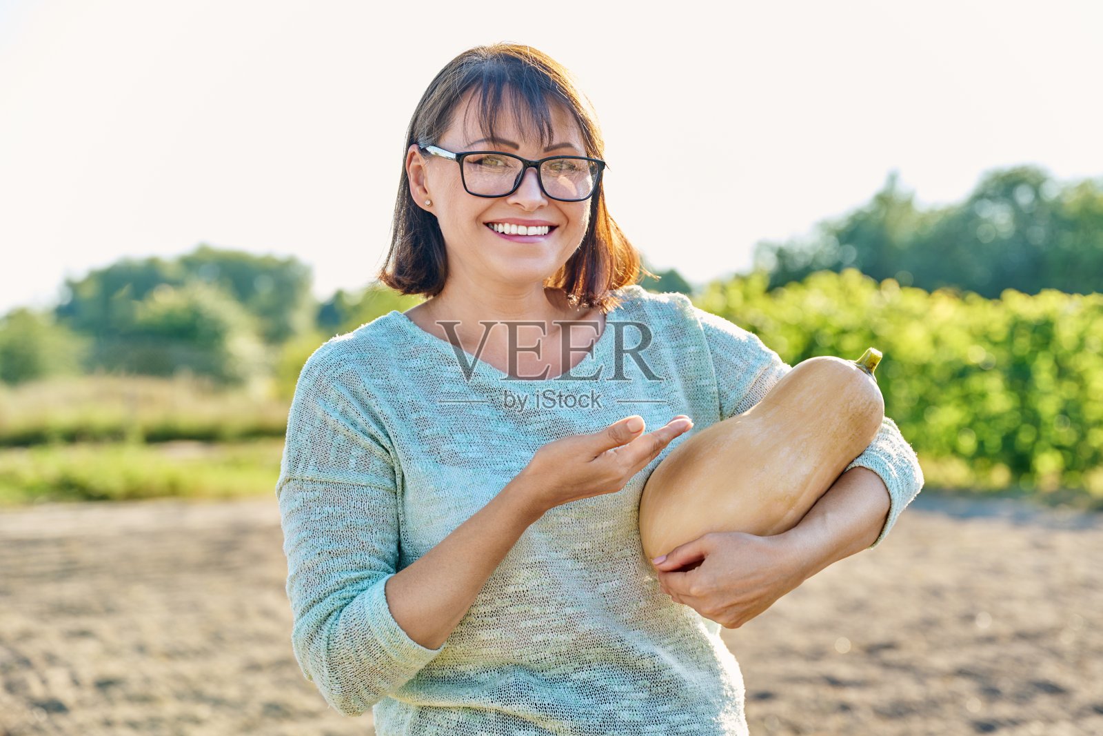 秋天,农场里快乐的女人抱着成熟的南瓜照片摄影图片