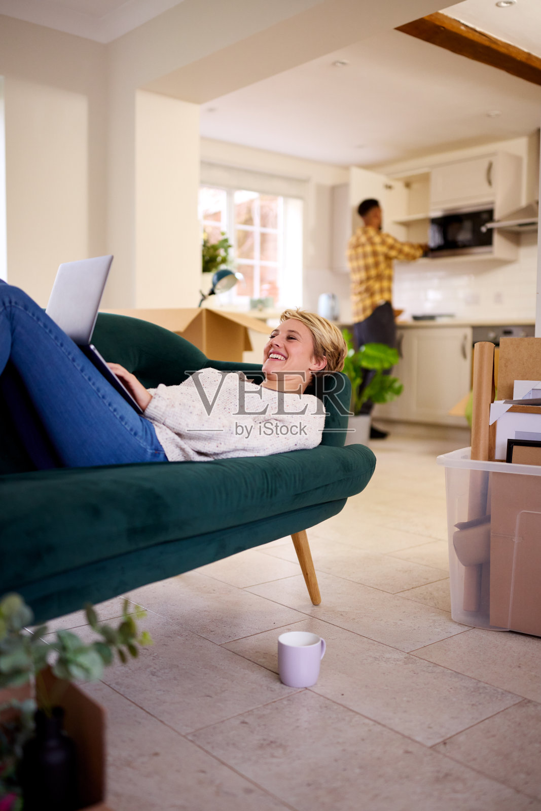 夫妇搬到新家后打开箱子,女人躺在沙发上用笔记本电脑照片摄影图片