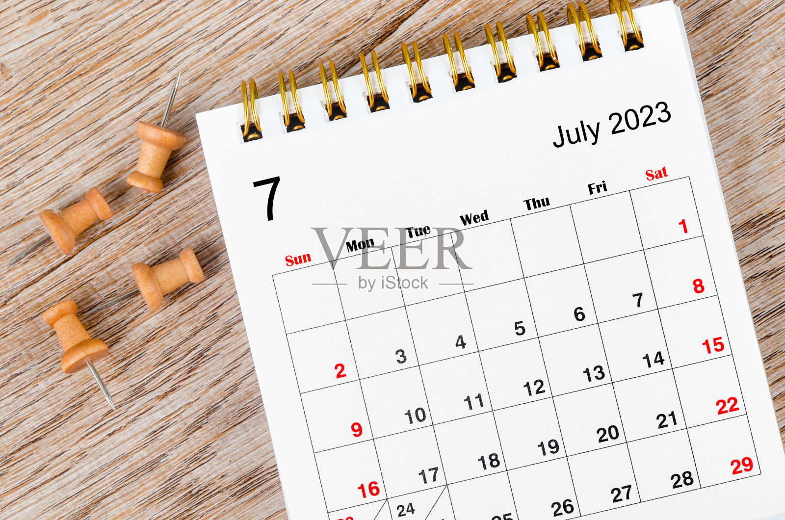 2023年7月的2023年每月台历,木制背景上有别针。照片摄影图片