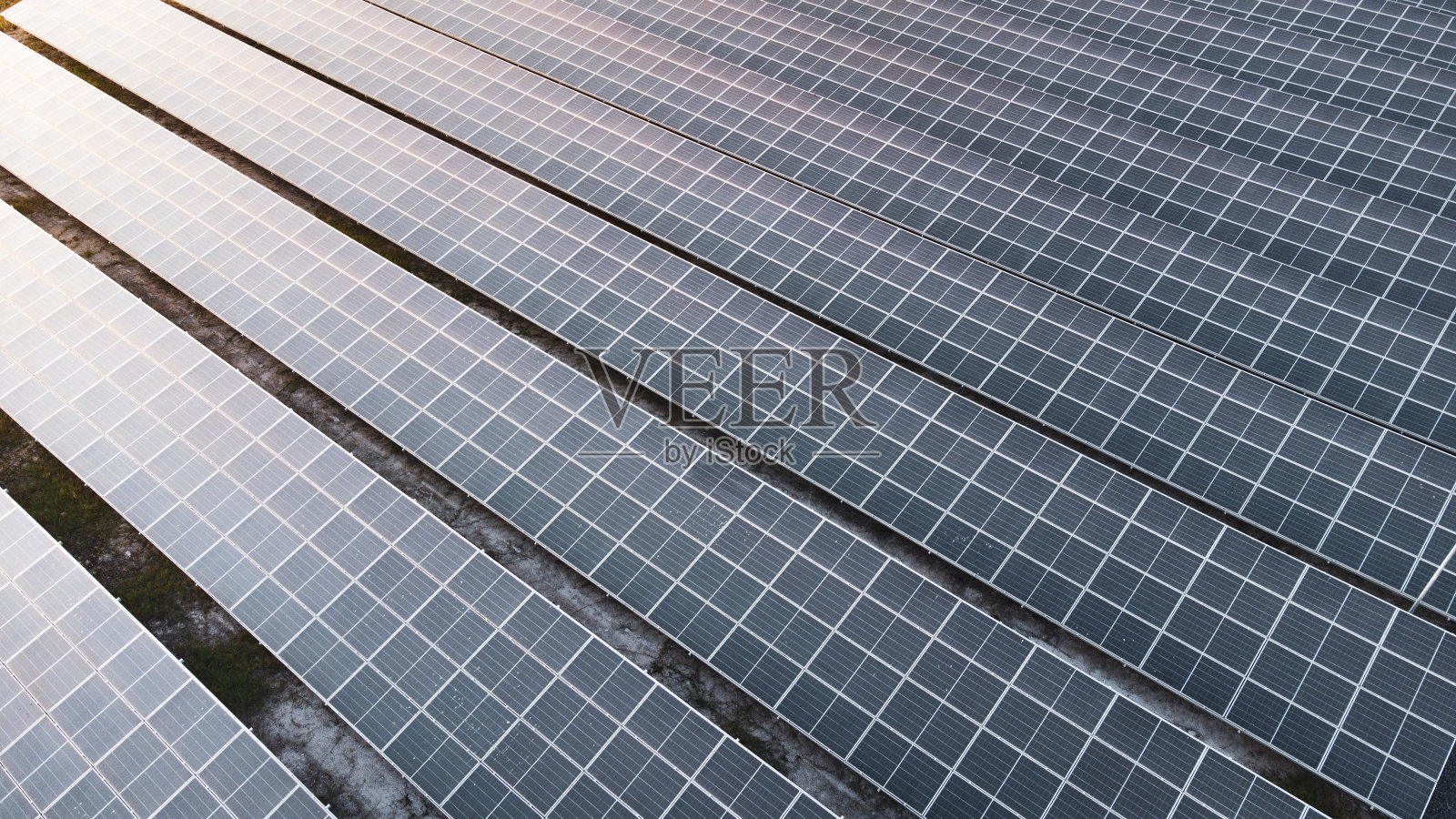 飞越太阳能电池农场旁边的自然绿色农场周围的大型工业厂区。太阳能发电厂为该行业提供可再生能源。照片摄影图片