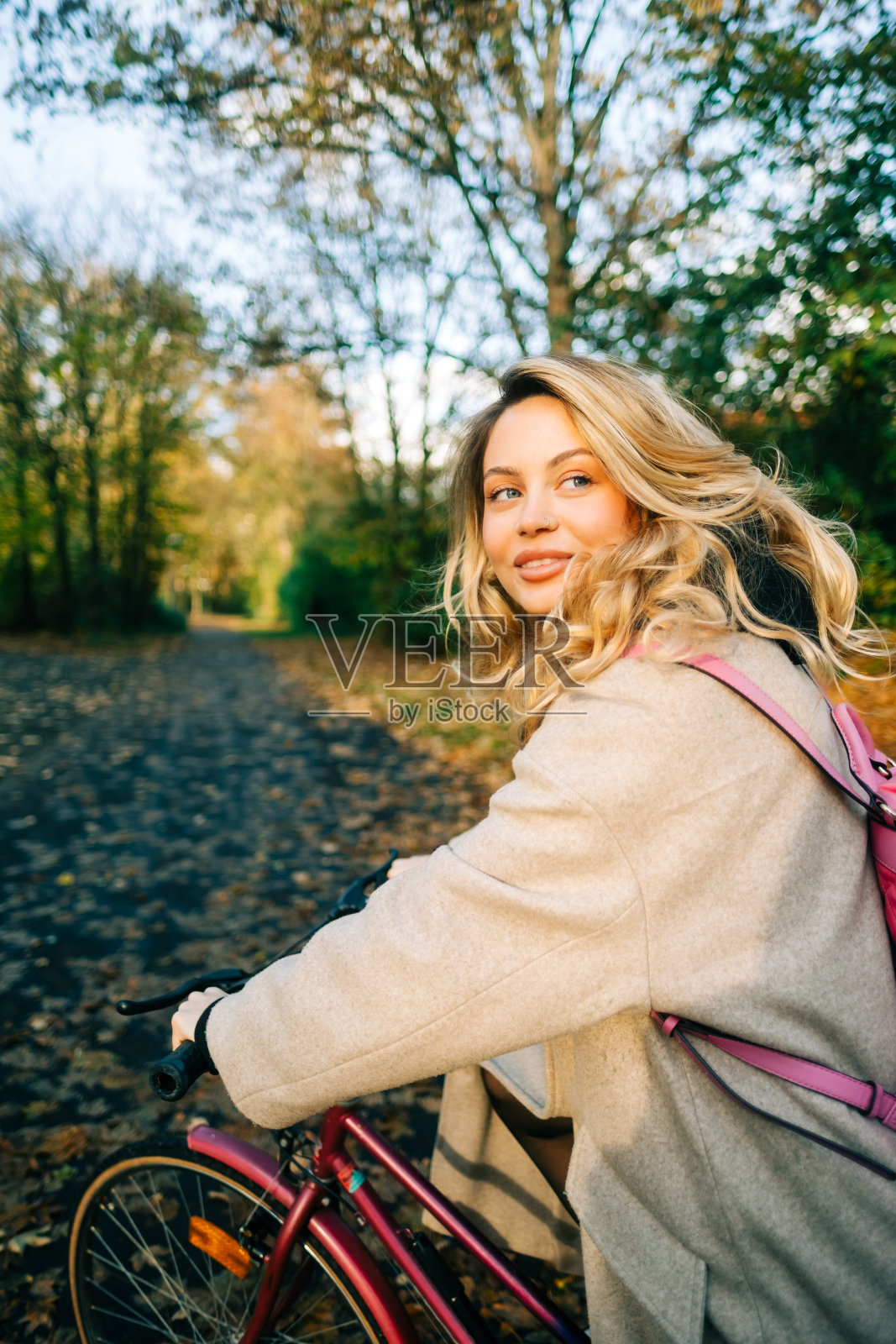 年轻迷人的白人女子骑自行车在公园在温暖的一天在秋天。照片摄影图片