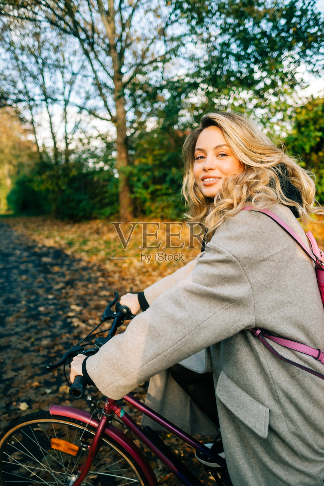 年轻迷人的白人女子骑自行车在公园在温暖的一天在秋天。照片摄影图片