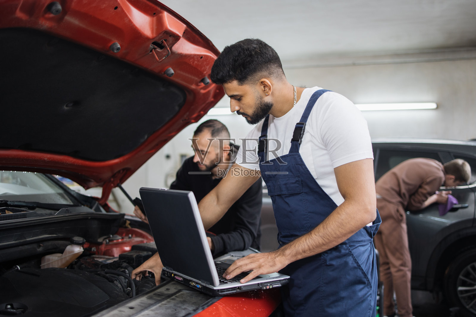 年轻的大胡子男同事汽车技师修理汽车发动机问题照片摄影图片