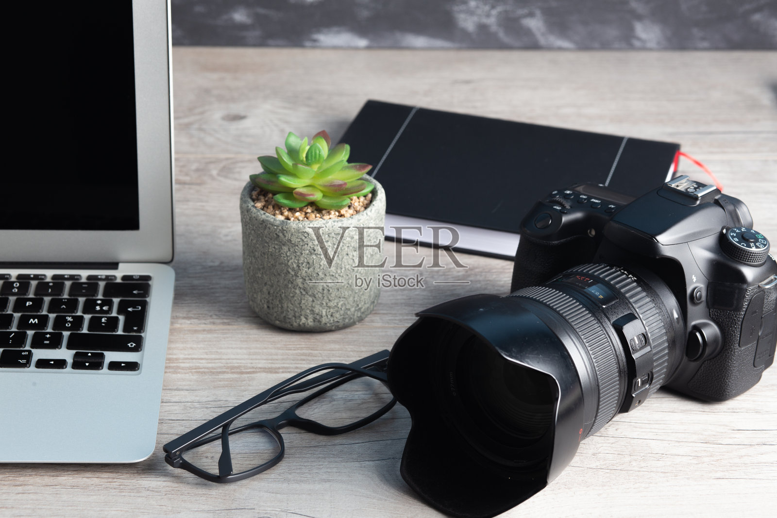摄影师工作站有相机,笔记本电脑,眼镜放在木桌上照片摄影图片
