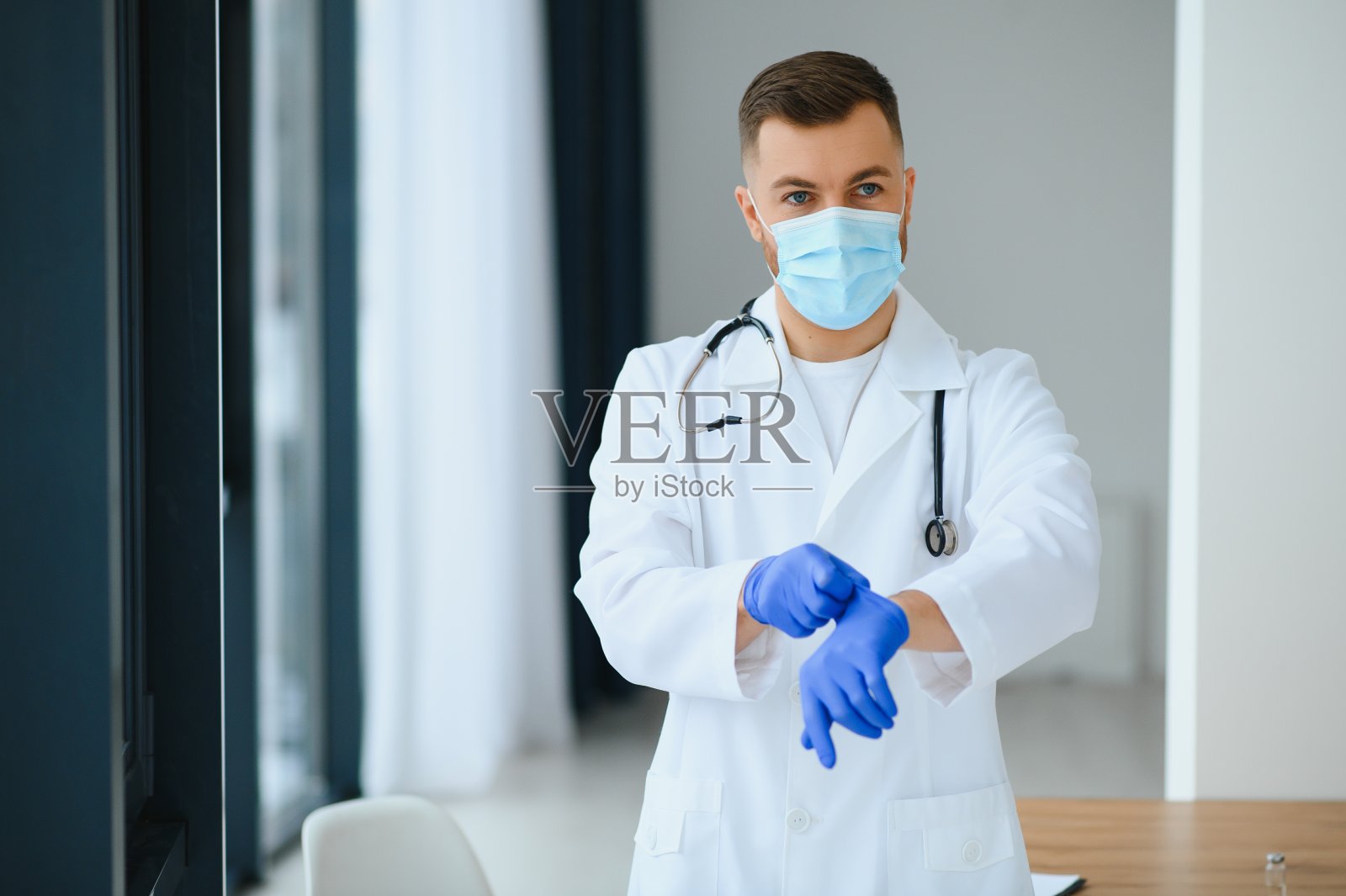 戴着外科口罩的男医生的肖像,准备帮助患有冠状病毒或covid病毒的患者。照片摄影图片