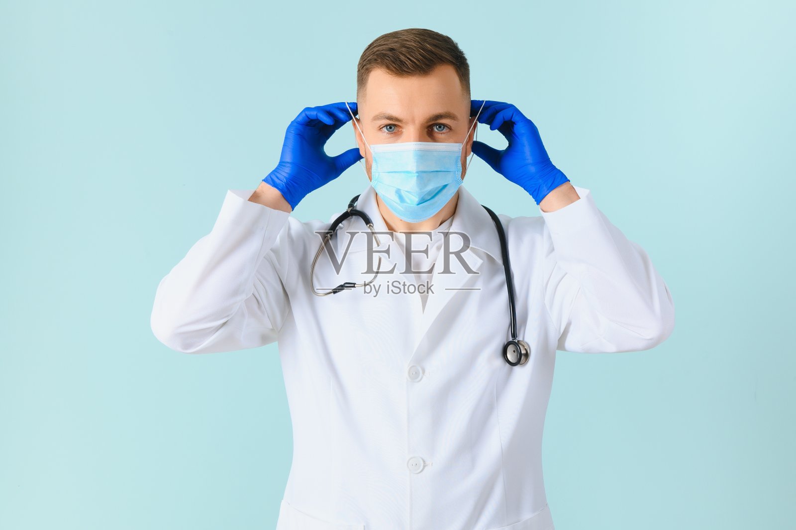 彩色背景上戴医用口罩的男医生照片摄影图片