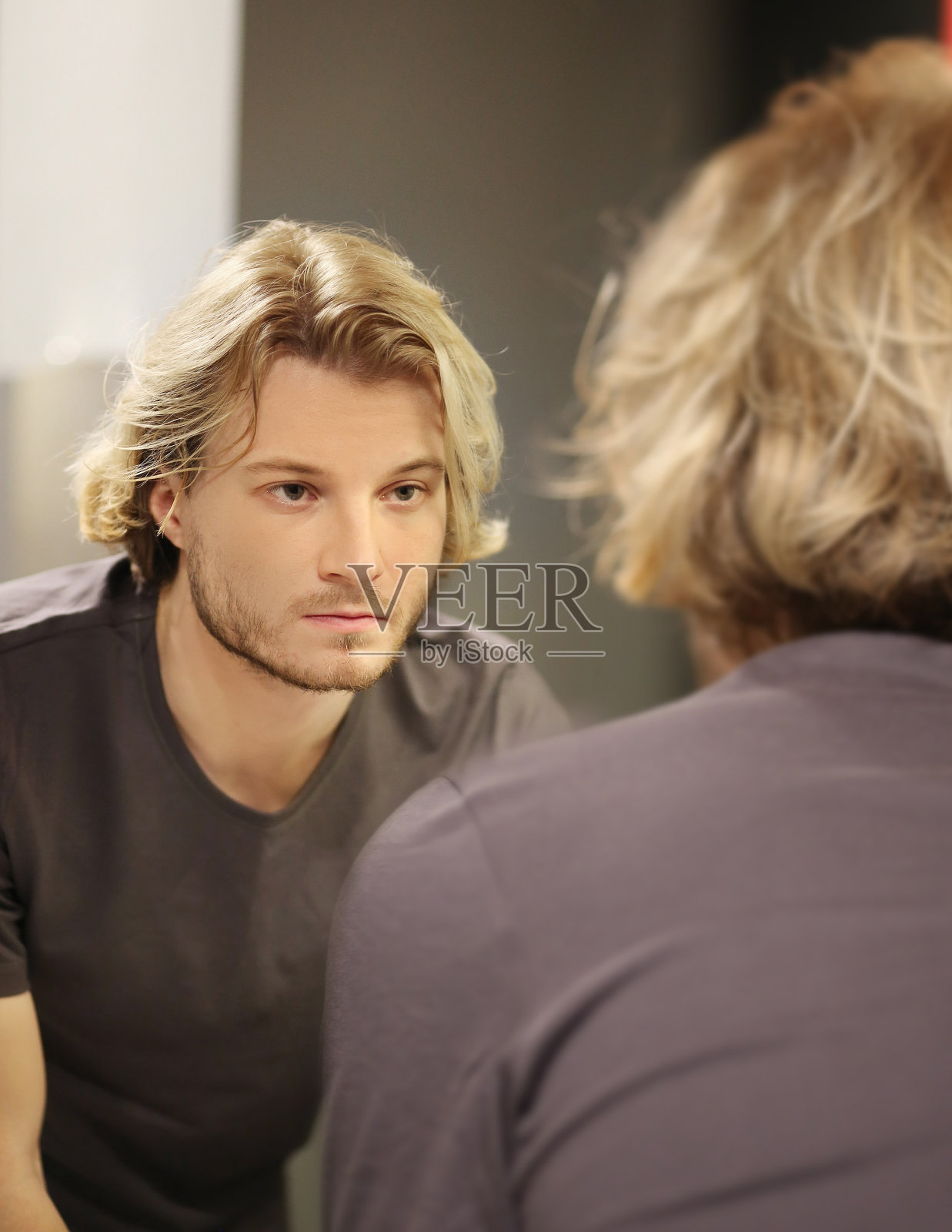 年轻人看着镜子,梳着头发,把问题放在脸上照片摄影图片