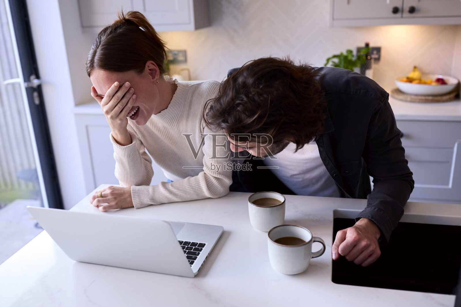 情侣在家中厨房的柜台上看笔记本电脑照片摄影图片