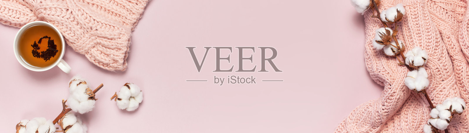 女性粉色针织毛衣,分枝的棉花,一杯茶在粉彩背景俯视平lay。女士冬季服装时尚外观。精致的棉花花。生活方式温和的女性背景照片摄影图片