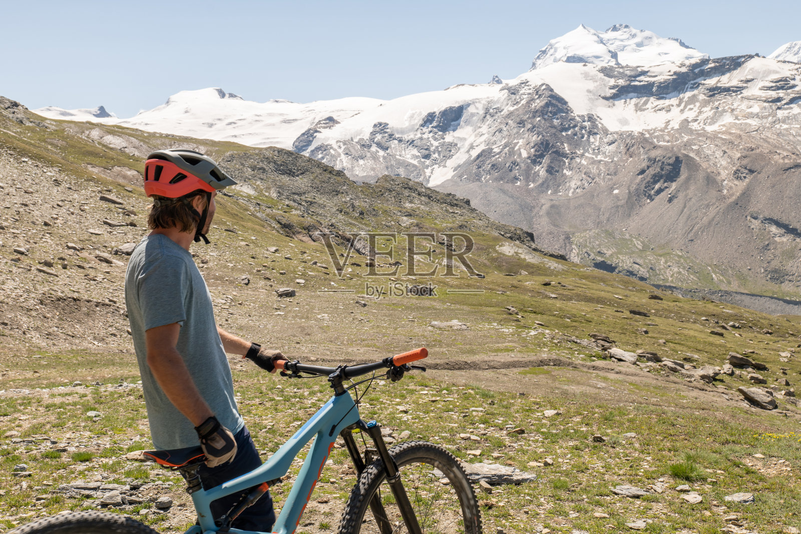 男山地自行车手欣赏小路上的风景,远处是冰川照片摄影图片