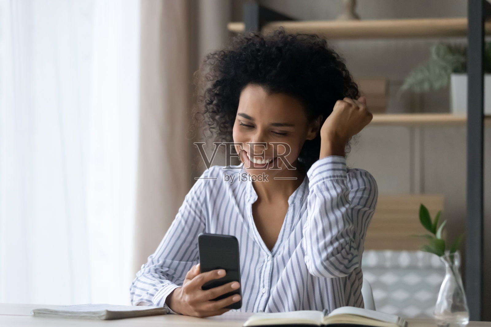 兴奋快乐的非洲年轻女子庆祝网上胜利。照片摄影图片