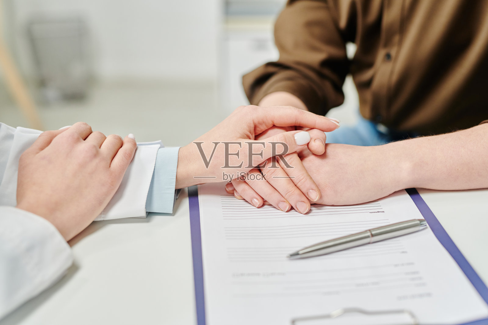 在护理过程中,白大褂医生的手放在女病人的手上照片摄影图片