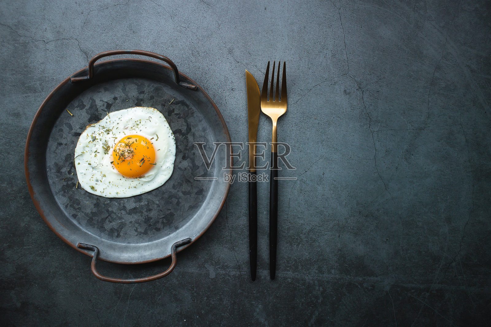 自制煎蛋在一个老式的锅和时尚的餐具在黑暗的背景。从上面看。文本复制空间。照片摄影图片