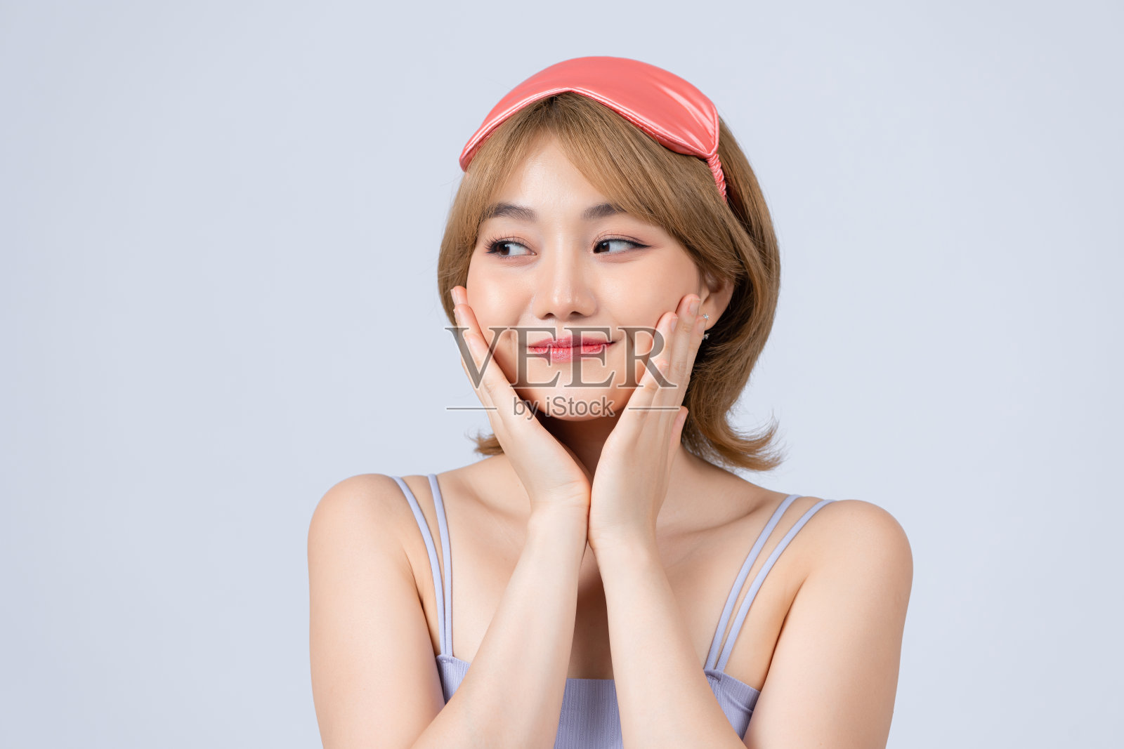 年轻兴奋的笑女人拿着睡眠面具在额头上,从下面看,在睡衣派对上玩得很开心照片摄影图片