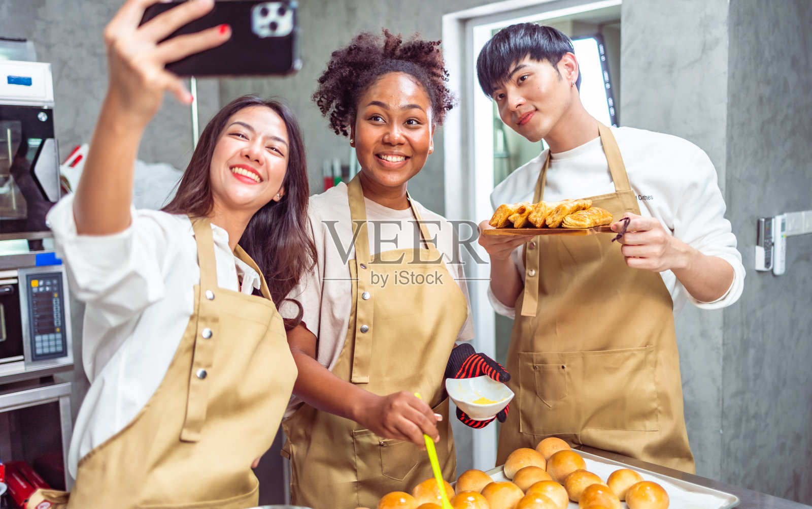 烹饪课的学生在厨房里为食谱混合配料。一群年轻人在烹饪课上自拍。照片摄影图片