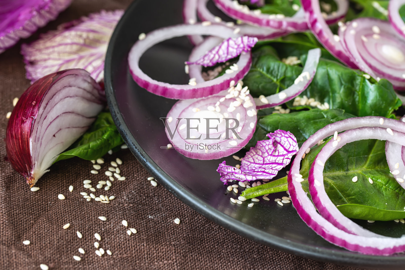 新鲜健康的维生素沙拉。用橄榄油和芝麻调味的红洋葱、菠菜和青菜沙拉。健康食品。素食食物。生食饮食。健康的生活。有机食品。照片摄影图片