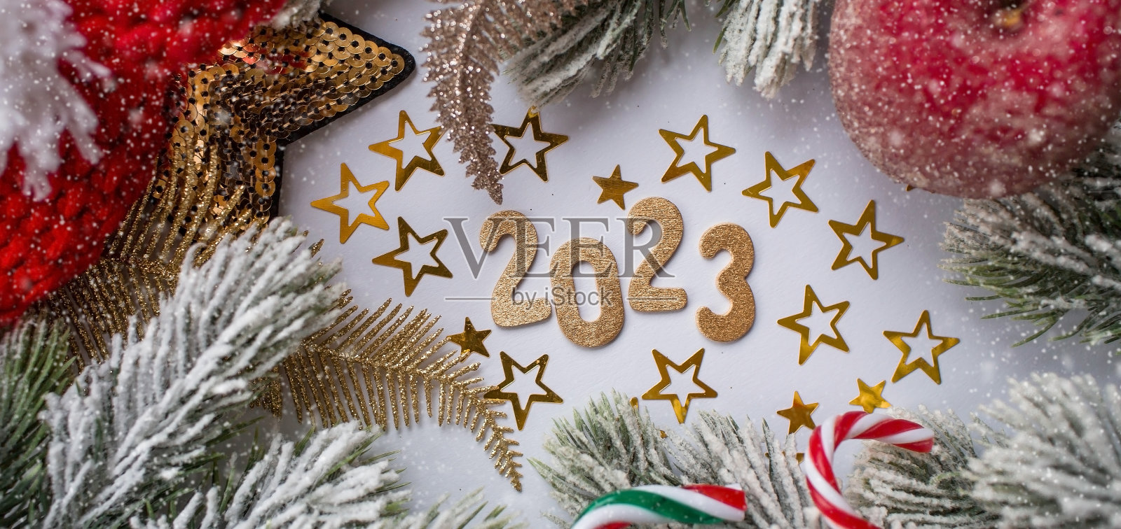 新年快乐,圣诞快乐。金色数字2023、雪、冷杉树枝、圣诞树玩具和白色背景上的金色星星。横幅。的邀请。照片摄影图片