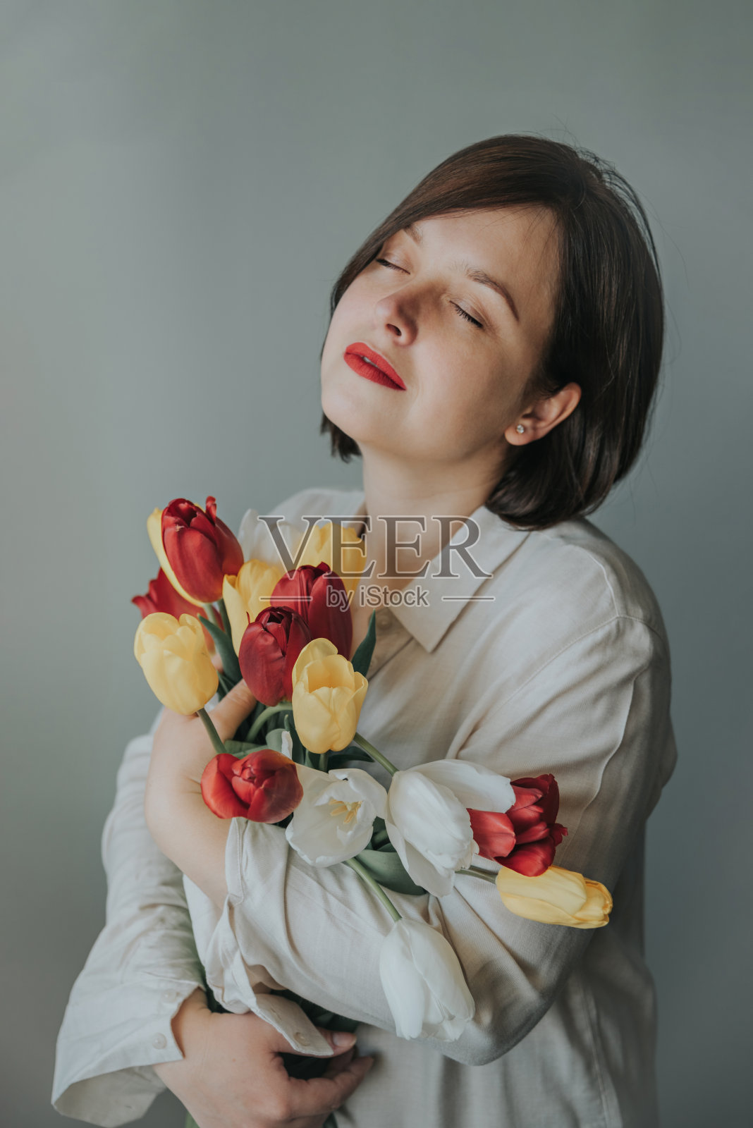一个女孩拿着一束郁金香的肖像。照片摄影图片