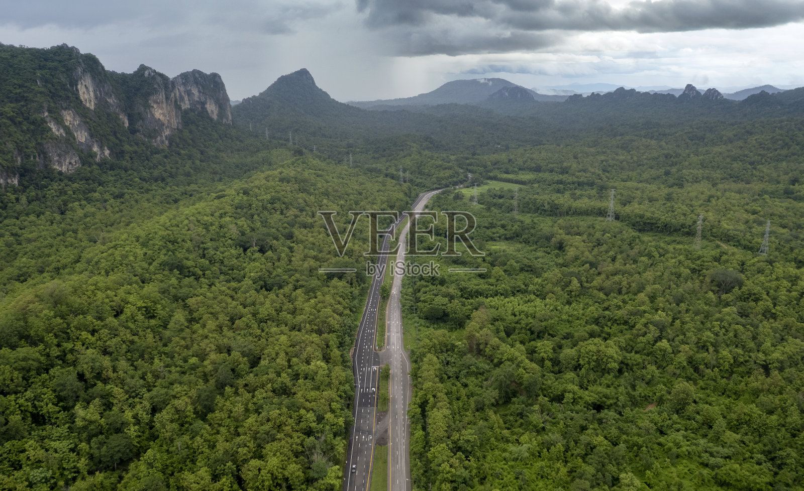 乡间小路穿过绿树成荫的树林和山峦照片摄影图片