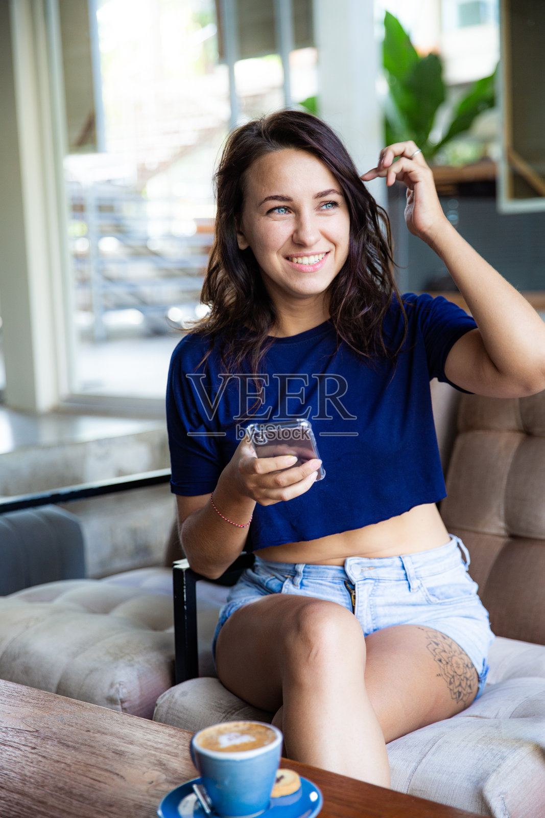 年轻的自由职业者用手机工作她坐在桌子旁。照片摄影图片