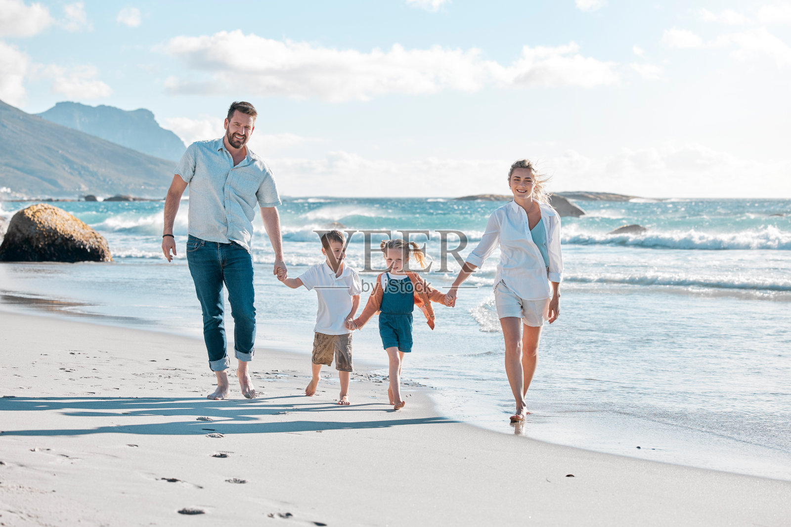 在海边度假的幸福白人家庭合影:明媚夏日里,孩子们与父母享受美好假期,一家人在明亮背景下放松微笑照片摄影图片