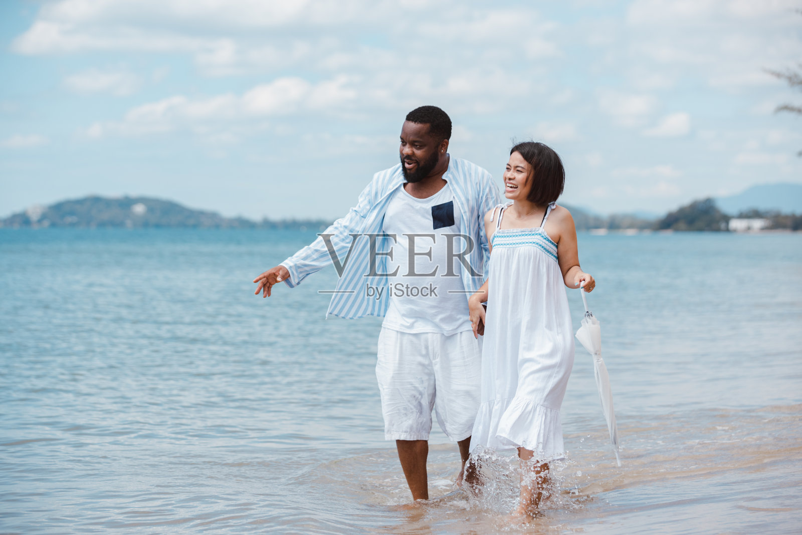 一对美国非洲裔夫妇在海滩上散步时玩得很开心照片摄影图片