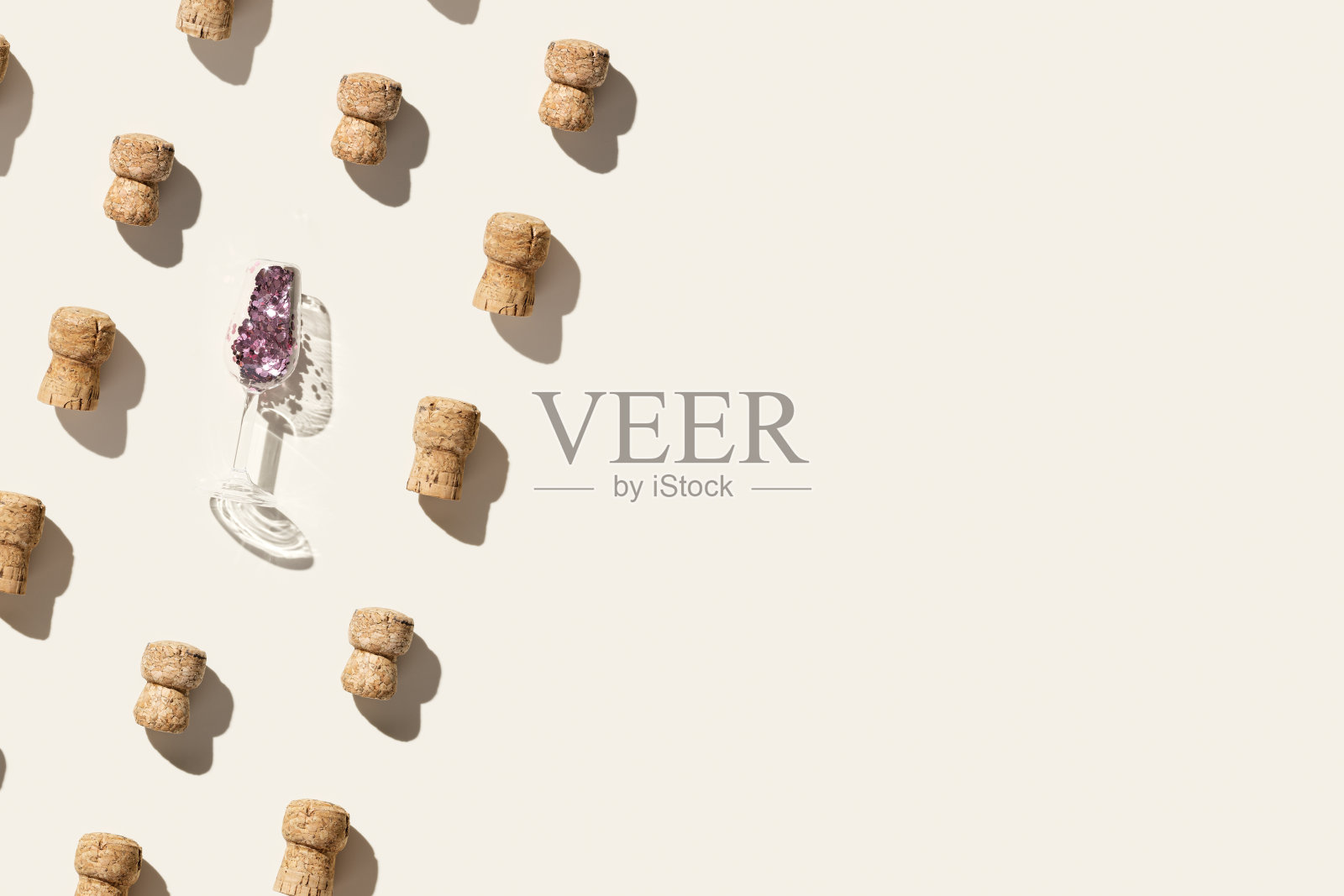 图案与香槟软木塞和酒杯闪闪发光的米色背景,硬光和阴影。夏季酒饮概念,瓶盖由气泡酒,重复图案俯视照片摄影图片