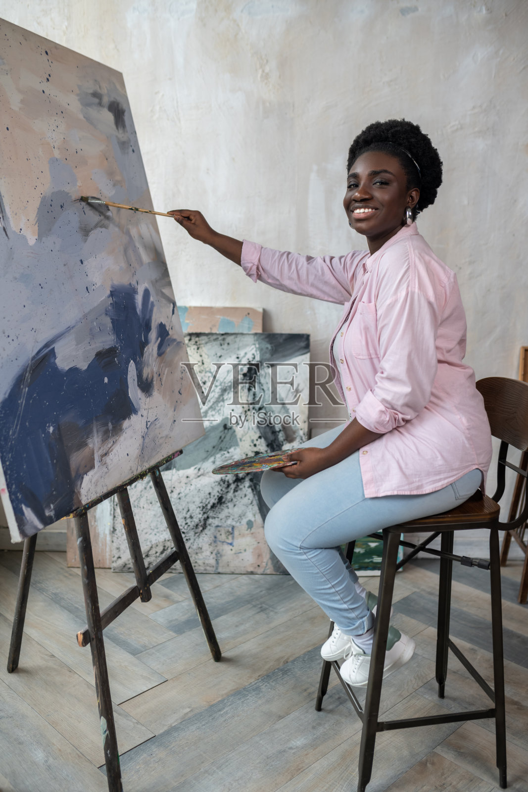 一个深色皮肤的女人坐在画架旁边画画照片摄影图片