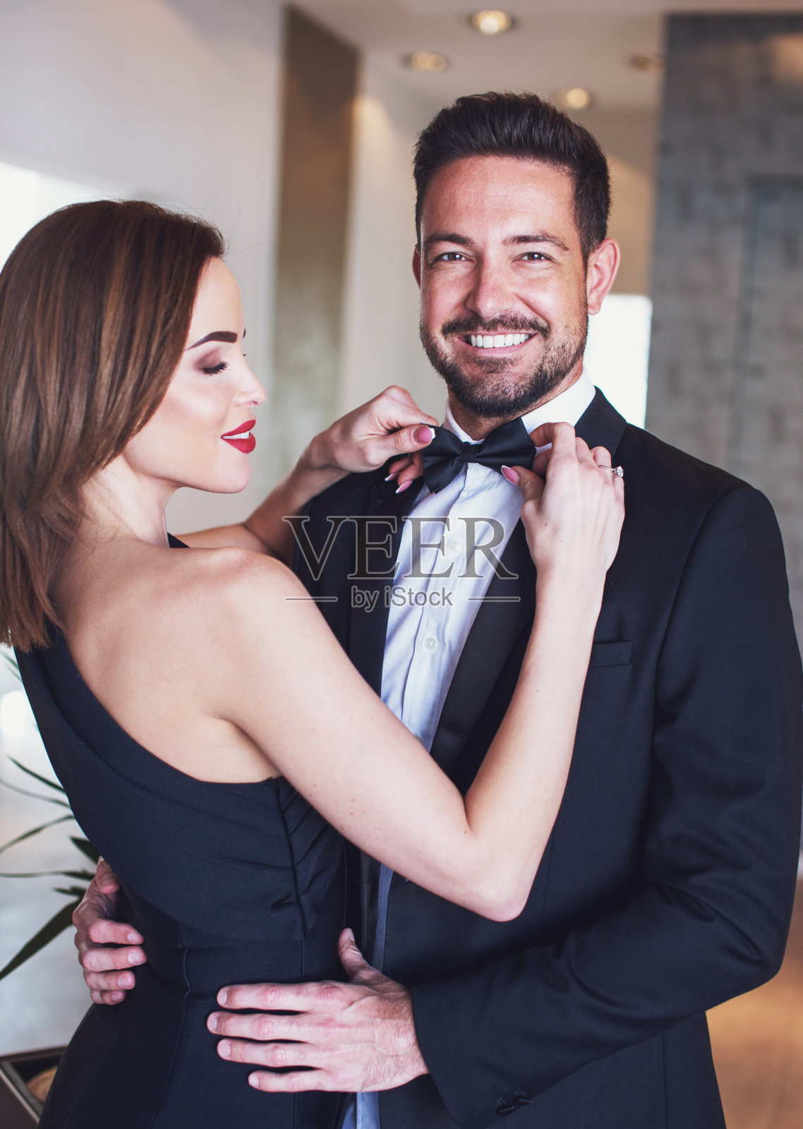 年轻的女人正在为快乐的男人调整领结照片摄影图片