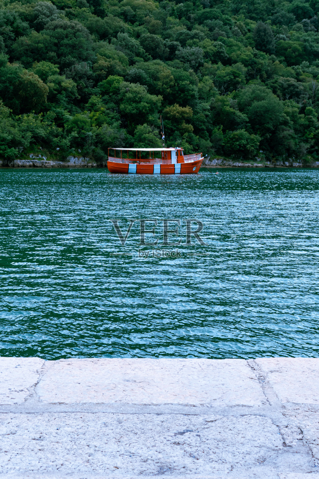 侧观水上小船与背景山,绿色景观。照片摄影图片