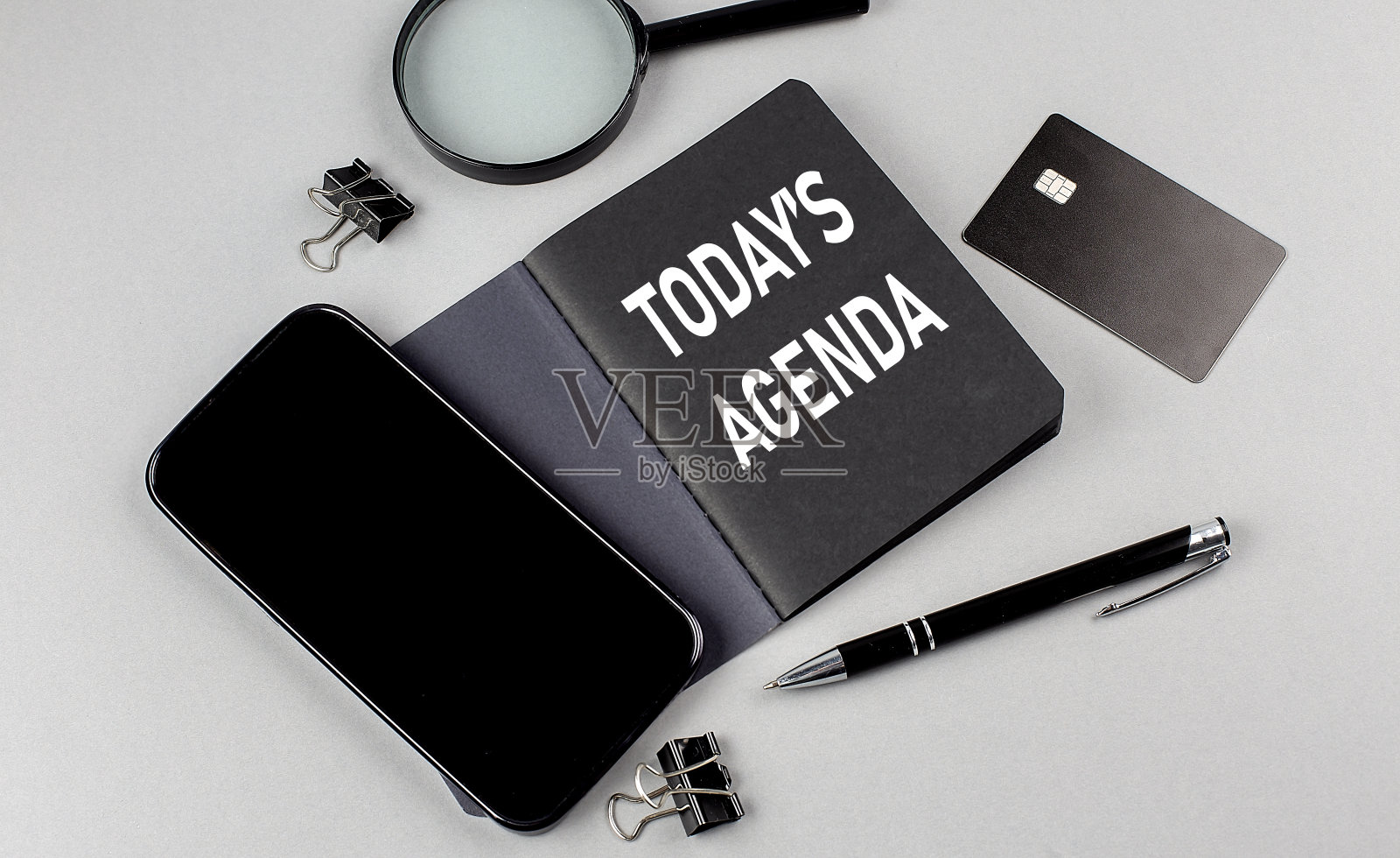 今天的议程文本写在黑色笔记本与智能手机,放大镜和信用卡照片摄影图片