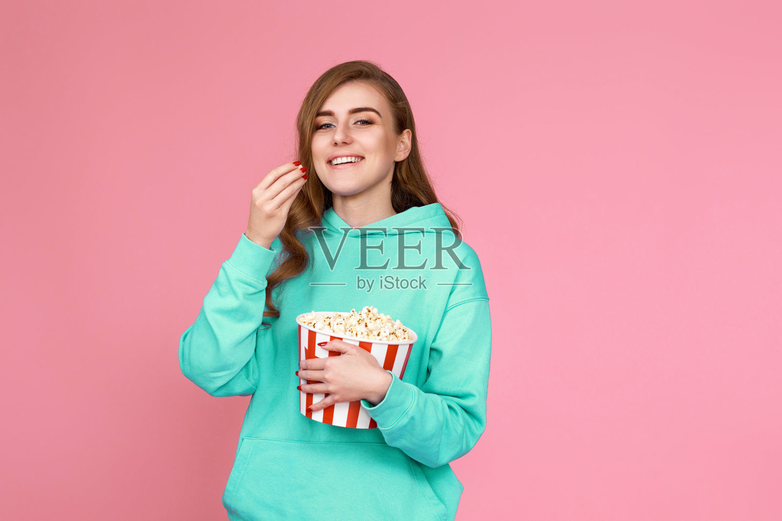 穿着运动衫的女人在看电影,吃爆米花照片摄影图片