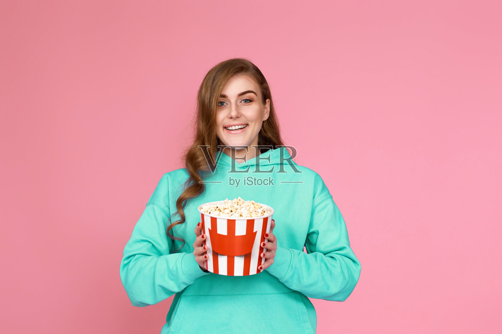 穿着运动衫的女人在看电影,吃爆米花照片摄影图片