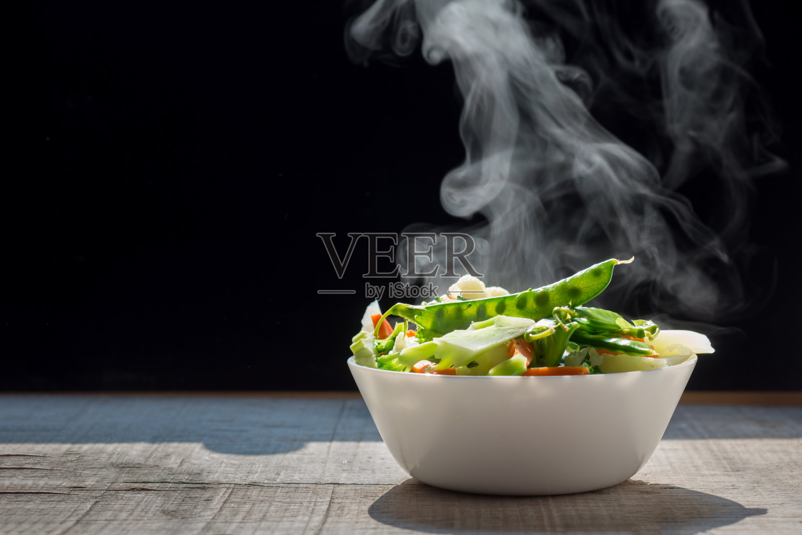 热气腾腾的杂菜在白色的碗上,深色的背景选择性聚焦。照片摄影图片