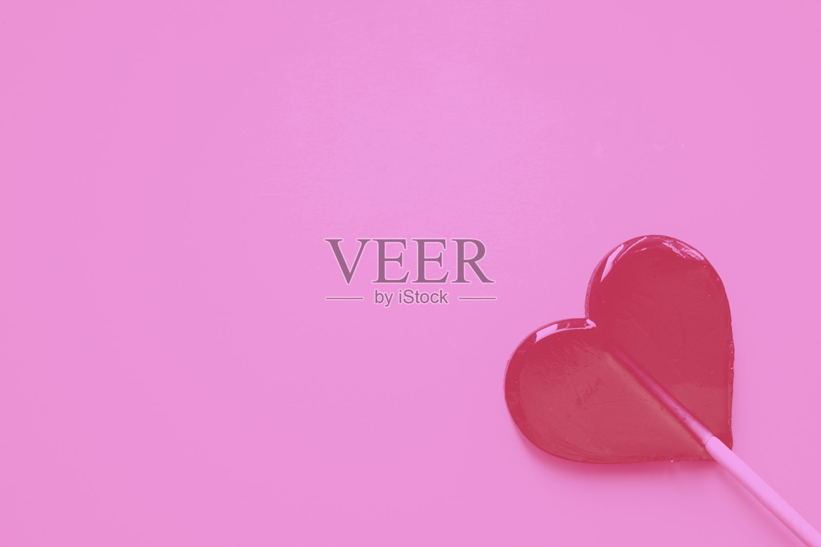 粉红色背景上的心形棒棒糖,颜色是洋红色的。情人节,3月8日母亲节。空间复制。照片摄影图片