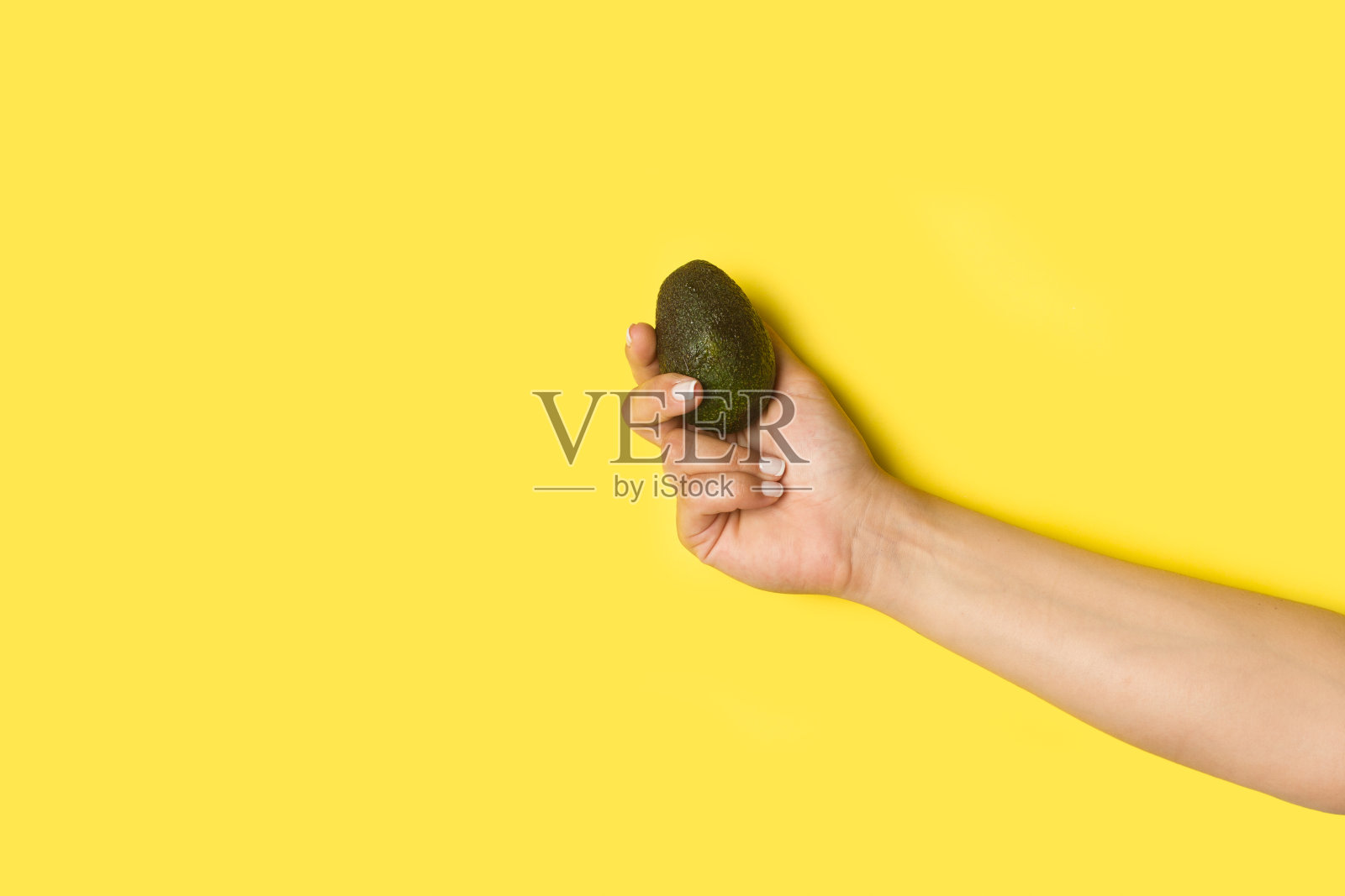 女人手握牛油果在一个黄色的背景复制空间照片摄影图片