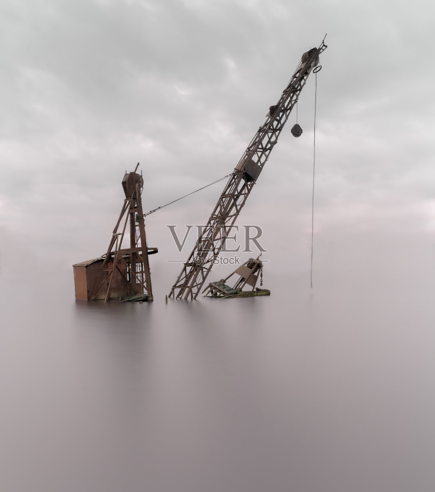 在阴云密布的天空下,海上废弃的起重机照片摄影图片